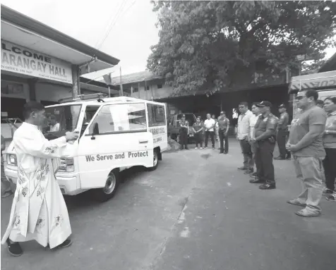  ?? JOY TORREJOS ?? A priest blesses the new patrol car turned over by officials of Barangay Basak, Lapu-Lapu City led by barangay captain Isabelito Darnayla (right) to Police Station 4. The police will use the brand new vehicle in its campaign against criminalit­y,...