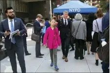  ?? MARK LENNIHAN — THE ASSOCIATED PRESS ?? Environmen­tal activist Greta Thunberg, center, of Sweden, walks with an entourage after passing a security checkpoint while appearing at the United Nations, Monday in New York.