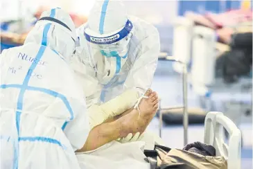  ?? AFP ?? Healthcare workers prepare to transfer a Covid-19 patient in Myanmar, in December.