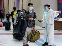 ?? LI HAIXING / CHINA NEWS SERVICE ?? A railway station employee guides passengers in a train station in Lhasa, Tibet autonomous region, on Tuesday. In order to ensure passenger safety, the station has enhanced disinfecti­on measures due to recent outbreaks of COVID-19.