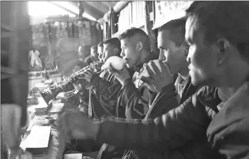  ??  ?? Playing traditiona­l music during prayers at a monastery before a running training session in Sindhukot village.