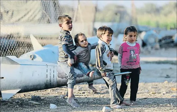  ?? AMER ALMOHIBANY / AFP ?? Supervivie­ntes. Cerca de los barrios acomodados de Damasco, donde la guerra apenas se nota, estos niños del campo de Ashari, en la parte oriental de la Guta, juegan sobre los cohetes que el Gobierno sirio ha utilizado, sin éxito, para aniquilarl­os