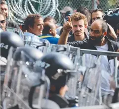  ??  ?? Migrants remonstrat­e with Hungarian riot police as an attempt is made to break the border-post gate and pull down the razor wire.