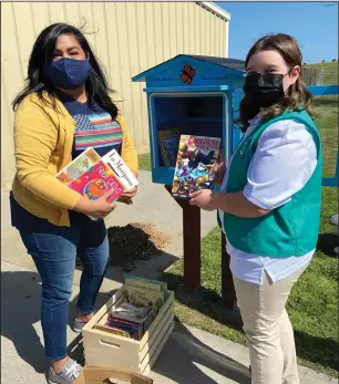  ?? COURTESY PHOTOS BY SABRINA WILLIS-BARTRAM ?? Maria Ditmore and Abby Stroud load books into the Little Library they built in front of the Migrant Housing Center on Harney Lane Saturday.