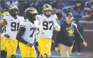  ?? AP/CARLOS OSORIO, FILE ?? Michigan head coach Jim Harbaugh walks out April 13 with players during the team’s annual spring NCAA college football game in Ann Arbor, Mich. Harbaugh seems to be set up for success at Michigan in his fifth season, leading a program that is a popular choice to win the Big Ten.