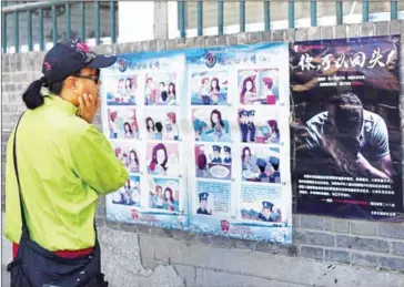  ?? GREG BAKER/AFP ?? A woman looks at a propaganda cartoon warning residents about foreign spies, in an alley in Beijing, yesterday.