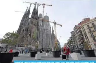  ??  ?? BARCELONA: A woman pulls a shopping trolley close to the Sagrada Famila (Holy Family) Basilica in Barcelona. —AFP