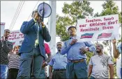  ?? LANNIS WATERS / THE PALM BEACH POST ?? James Leger (with megaphone) outside Palm Beach Gardens High on May 11 asks a teacher to apologize for his Haiti comments.