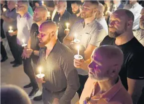  ?? MICHAEL LAUGHLIN/SOUTH FLORIDA SUN SENTINEL ?? Men hold candles while watching a video as Wilton Manors celebrates the life of Mayor Justin Flippen on Friday at The Venue. He is remembered for his commitment to faith and LGBTQ rights.