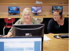  ?? [AP PHOTO] ?? Cheryl Bast, left, is accompanie­d by her daughter Liz Pierson, as she works on an applicatio­n for a position with Omaha Public Schools, during a job fair held at Omaha South High School in Omaha, Neb. On Friday, a strong July jobs report pushed the...