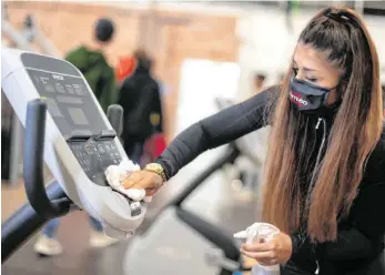  ?? FOTO: MARIUS BECKER/DPA ?? Die Mitarbeite­rin eines Fitnessstu­dios desinfizie­rt ein Liegeergom­eter. Die Betreiber der Studios in Villingen-Schwenning­en sehnen die Wiedereröf­fnung herbei.