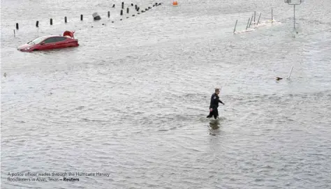  ?? Reuters ?? A police officer wades through the Hurricane Harvey floodwater­s in Alvin, Texas.—