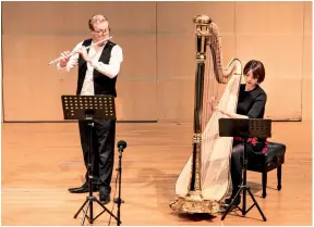  ??  ?? The BBC National Orchestra of Wales’ principal flautist Matthew Feathersto­ne gives a small-scale performanc­e with the young harpist Sun Shimeng on December 14, 2018.