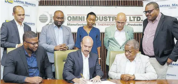  ?? ?? Patrick Kumst, (front centre) managing director, Omni Industries, signs the deal with NCB Capital Markets to help it raise capital to expand and enter the Central American market. Timar Jackson (left) assistant-vice president at NCB Capital Markets, and Von White (front right) chairman, Omni Industries, look on while members of both companies bear witness in the back row.