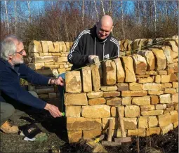  ??  ?? Dr Richard Love teaches student Stevie Gordon the 5,000-year-old craft of dry stone walling following a surge in demand for the ancient technique