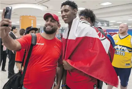  ?? CHRIS YOUNG/THE CANADIAN PRESS ?? R.J. Barrett, right, has his photo taken with a well wisher after arriving at Toronto’s Pearson Airport on Monday night with other members of Canada’s under-19 basketball team after winning the gold medal at the U19 FIBA World Cup in Cairo.