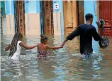  ??  ?? A man and his children wade through the water forced into Havana by Hurricane Irma.