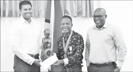  ?? ?? Minister of Sport, Charles Ramson Jr. (left) made the presentati­on to Olympic medallist Michael Parris in the presence of Director of Sport, Steve Ninvalle.