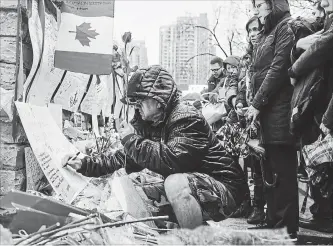  ?? GALIT RODAN THE CANADIAN PRESS ?? A man writes a message at a growing memorial on Yonge Street in Toronto on Tuesday.