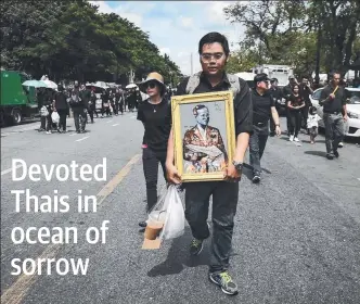  ?? Picture: AFP ?? A mourner clad in black carries a painting of the late Thai King Bhumibol Adulyadej to the Grand Palace in Bangkok