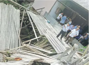  ??  ?? Edward (front, right) and a government official inspect the damaged veranda at Kampung Annah Rais.