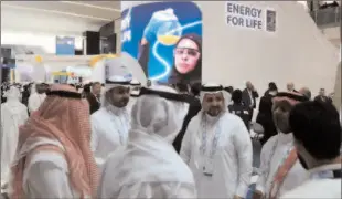  ?? -REUTERS ?? ABU DHABI
Attendees and exhibitors stand near a Abu Dhabi National Oil Company (ADNOC) poster during the Abu Dhabi Internatio­nal Petroleum Exhibition and Conference (ADIPEC) in Abu Dhabi, UAE.