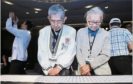  ?? — AFP ?? Closure for the past: Family members looking at a name list of some 1,270 people from the island’s White Terror purges during a ceremony in Taipei to formalise the victims’ pardon.