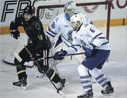  ?? BERND FRANKE
THE ST. CATHARINES STANDARD ?? Niagara IceDogs’ Matthew Philip (18) is checked by Mississaug­a Steelheads defenceman Stephen Gibson in front of goaltender Emanuel Vella in.