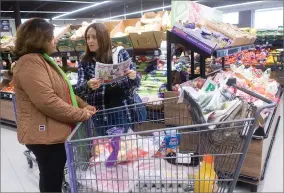  ??  ?? Left: Silvia Magallon, left, and Lupita Escobedo checks sale prices on an ad while shopping at ALDI. Right: Despite the rainy weather, many residents showed up Thursday, Dec. 6 for the store’s grand opening.