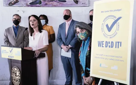  ?? CARL JUSTE cjuste@miamiheral­d.com ?? Miami-Dade Mayor Daniella Levine Cava, right, peers around the poster as Loreen Chant, president and CEO of the Health Foundation of South Florida, announces an initiative to encourage COVID-19 vaccinatio­ns at Dukunoo Jamaican Kitchen in Wynwood.