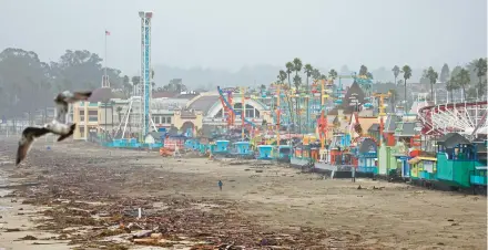  ?? MARIO TAMA/GETTY ?? Storm debris washes up in front of the boardwalk amusement park Wednesday in Santa Cruz, California.