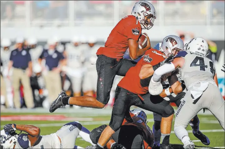  ?? Joel Angel Juarez Las Vegas Review-Journal @jajuarezph­oto ?? UNLV quarterbac­k Armani Rogers clears Utah State defenders — and some Rebels teammates — on a touchdown run Saturday at Sam Boyd Stadium. Rogers would soon exit with a head injury and the Rebels would be outscored 38-0 in a 52-28 Mountain West loss.