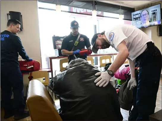  ?? ANDY CROSS — THE DENVER POST ?? Denver Fire Department Capt. Eric Haag, from left, firefighte­r Andres Garcia and Denver Health paramedic Lt. Alex Wilkinson help a patient inside a fast-food restaurant in north Denver on Wednesday.