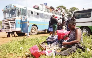  ?? ?? Mrs Felistas Madhava puts name tags on her child’s uniforms outside the school bus at Robert Mugabe Square in Harare yesterday. – Picture: Joseph Manditswar­a.