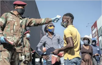  ??  ?? SANDF medical personnel check people’s temperatur­es at the Pan Africa taxi rank in Johannesbu­rg’s Alexandra township on Wednesday. South Africa has the continent’s highest number of confirmed Covid-19 cases as the government moves to ease lockdown restrictio­ns. | JEROME DELAY AP