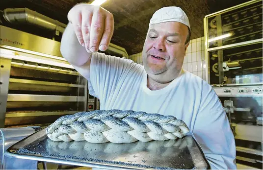  ?? Fotos: Marcus Merk ?? „Ohne Mohn fehlt irgendwas“, findet Harald Zott und bestreut das Berches. Das traditione­lle jüdische Brot wird seit 1914 in der Fischacher Bäckerei hergestell­t.