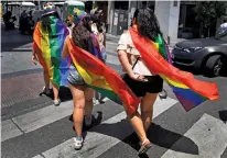  ?? — AFP ?? Young women wearing a rainbow flag, commonly known as the gay pride flag, walk in Madrid’s Chueca district
