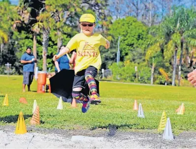  ?? PHOTOS BY GARY CURRERI ?? Above, Dania Beach’s Mae Li Wilcox flies through the air as part of her effort in the running broad jump event that was part of the annual Saints Internatio­nal Track and Field meet for home- schoolers at Tradewinds Park in Coconut Creek. Wilcox, who is...