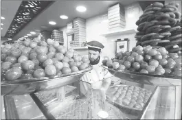  ??  ?? A man works at a shop selling traditiona­l Syrian sweets, that is owned by Syrian refugee Mazen Obeido who fled the conflict in his homeland.