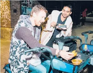  ?? LANNA APISUKH/THE NEW YORK TIMES PHOTOS ?? A Citi Bike doubles as a table as Neal Bakshi, right, and his friend Oliver Griffiths enjoy fajitas from a taco truck on April 23 in New York.