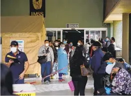  ?? ALEJANDRO TAMAYO U-T ?? La gente espera afuera las actualizac­iones del personal el viernes en la Clínica 20 de Tijuana, donde los pacientes con coronaviru­s están siendo tratados.