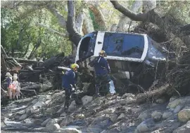  ?? THE ASSOCIATED PRESS ?? Members of the Los Angeles County Fire Department Search and Rescue crew work Wednesday on a car trapped under debris in Montecito, Calif. Dozens of homes were swept away or heavily damaged and several people were killed Tuesday as downpours sent mud...