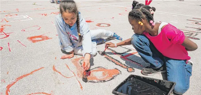  ?? MAXHERMAN/ FOR THE SUN- TIMES ?? Montessori School of Englewood students last week paint the name of one of the 291 schools across the country that has been affected by gun violence since the Sandy Hook shooting in 2012.