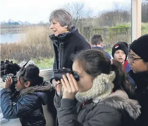  ?? Picture: PA. ?? Prime Minister Theresa May stands with schoolchil­dren inside a bird hide at the London Wetland Centre in South West London.