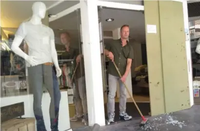 ?? FOTO JOHNNY GEURTS ?? Zaakvoerde­r Jack Schenk ruimt de glasscherv­en van de kapotgesla­gen glazen winkeldeur.