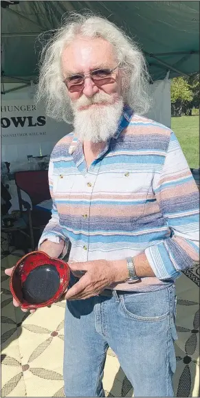  ?? (Special to NWA Democrat-Gazette/Sally Carroll) ?? Phillip Calkins shows off a heart-shaped bowl, an original design that he said is special to him. Calkins has an artificial aorta and said that led him to design a unique bowl for the Benton County Empty Bowls mission. The potter and retired certified public accountant heads up marketing and recruiting for the Bella Vista-based nonprofit.