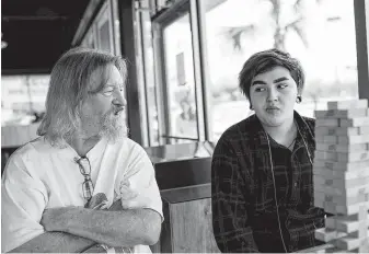  ??  ?? Dakota’s stepfather, Dan Monroe, joins him in a game of Jenga at a bubble tea shop. Days when Monroe has time before work to hang out with Dakota there feel like an escape from monotony.