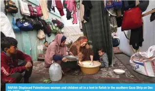  ?? —AFP ?? RAFAH: Displaced Palestinia­ns women and children sit in a tent in Rafah in the southern Gaza Strip on Dec 27, 2023.