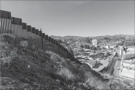  ?? PHOTOS BY JOHN BURCHAM / THE NEW YORK TIMES ?? A border wall bisects the twin cities of Nogales, Mexico, left, and Nogales, Ariz. For some locals, it remains a single place, split in two by the wall.