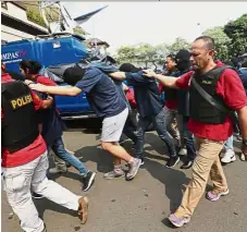  ??  ?? Caught: A file photo showing police officers escorting men arrested in a raid on a gay sauna to the police headquarte­rs in Jakarta. — AP